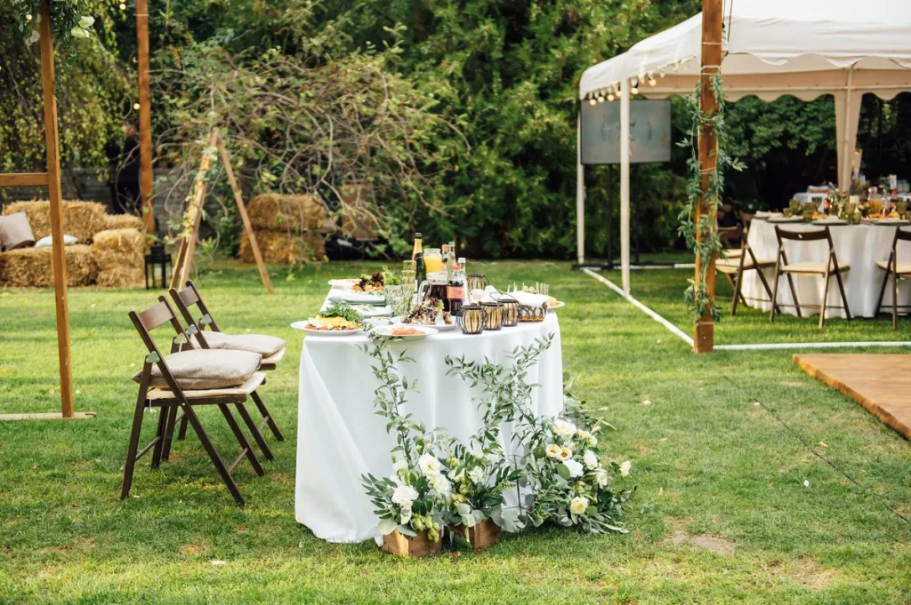 A beautiful picture of a backyard wedding, with a few tables set up and a pop-up pavilion.