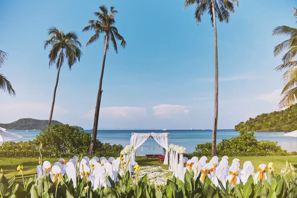 A picture of a wedding facing out towards the water, with palm trees around.