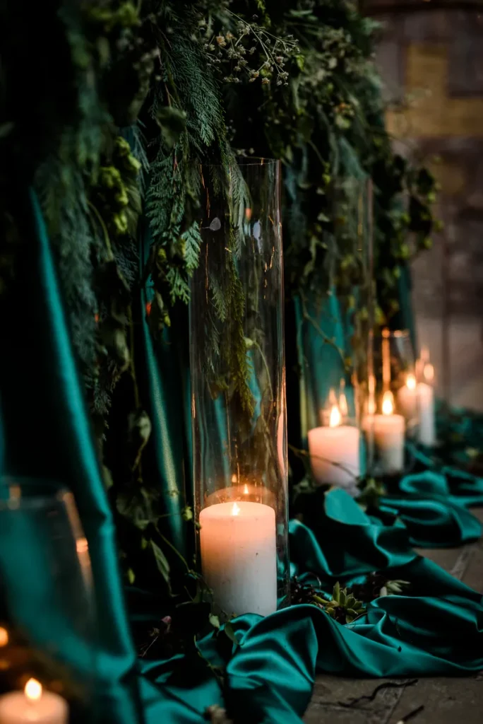Some emerald green satin lining an isle with candles to light it up.