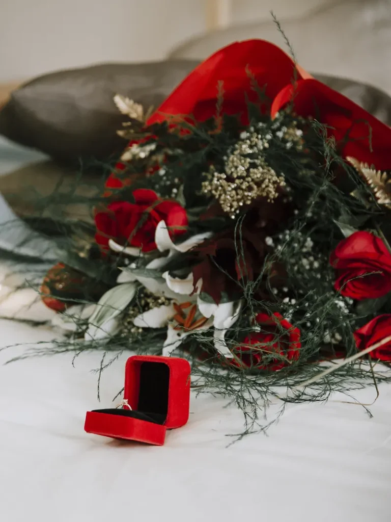 A Christmas themed bouquet and ring box, featuring lots of red, green and some snowy whites.