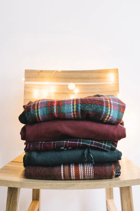 A chair with a bunch of cozy woolen blankets for guests to pick from in case they get chilly during the ceremony or reception.