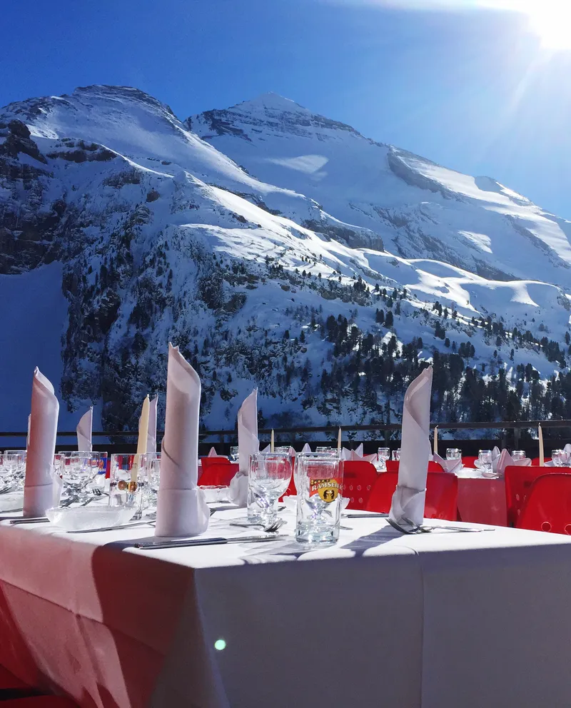 A ski lodge balcony set up for a fancy event overlooking large snowy mountains in the background.