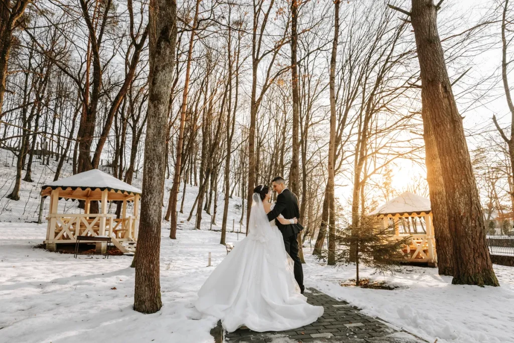 A forested path with a bride and groom on it and snow around.