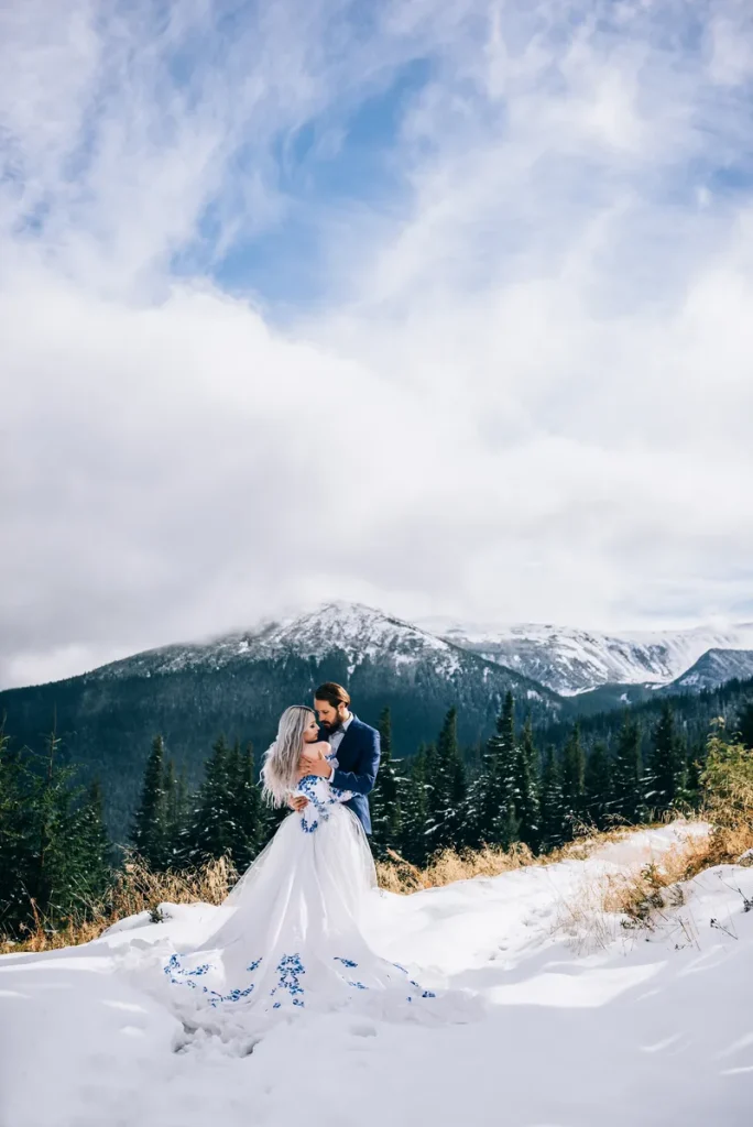 A picture of a lovely couple in the snow in front of a big snowy mountain.