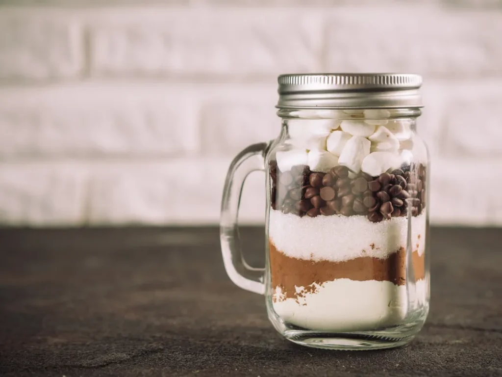 A mason jar full of hot cocoa supplies.