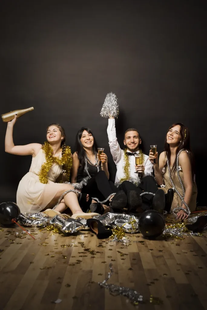 A group dressed in blacks, golds and whites with tinsel and confetti around them.
