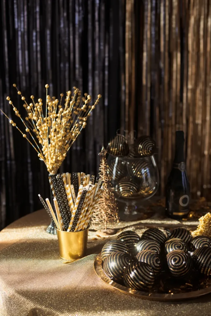 A table full of black and gold elegant decorations and straws.