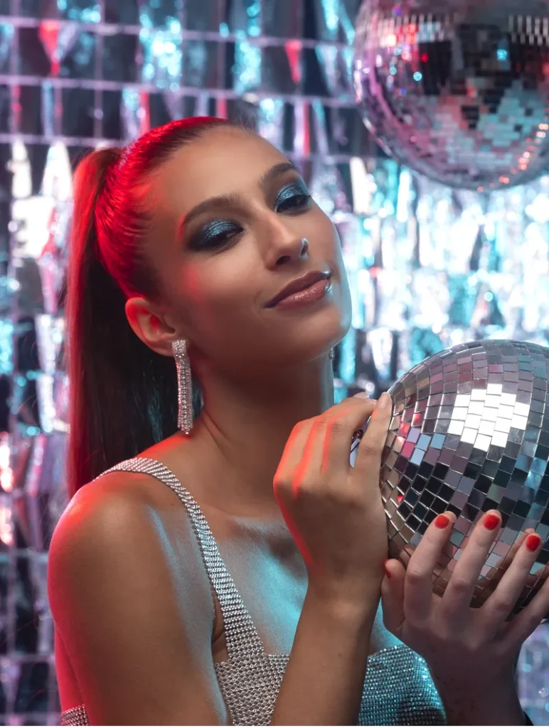 A bride in sparkly glam surrounded by disco balls and shiny new years decor.