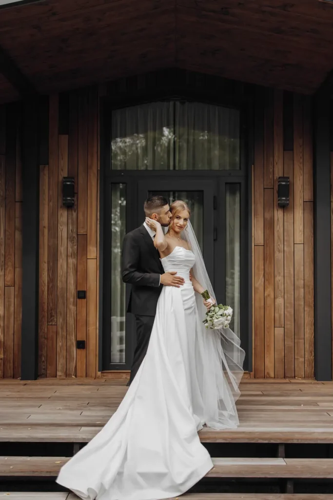 A bride and her groom getting their picture taken in front of a rustic cozy lodge.