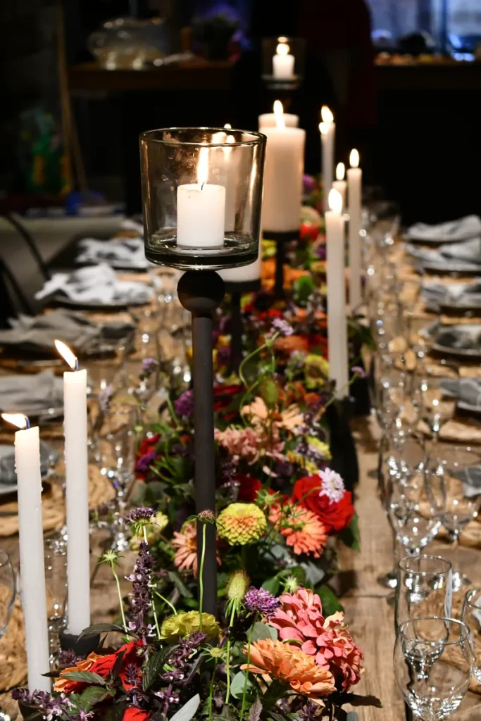 A candlelit long table with flowers in the center.