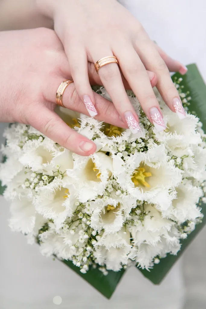 A flowery set of bridal nails, white slanted french tips with flowers coming out of them.