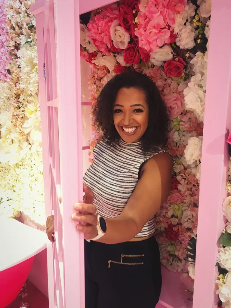 A picture of a woman going into a very cool photo booth with a bunch of flower decorations.